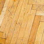 A heavily scratched wooden herringbone floor.