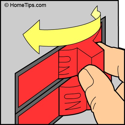 Man’s fingers holding a red circuit breaker switch, including an arrow pointing to a direction.