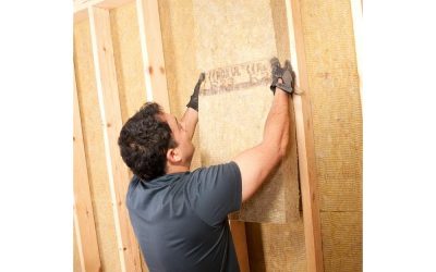 Man installing rock wool insulation between wall studs.