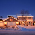 A house with the warm glow of holiday lights in the snow.