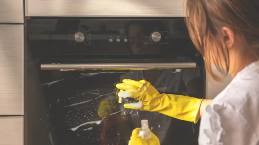 A girl cleaning oven at home