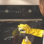 A girl cleaning oven at home