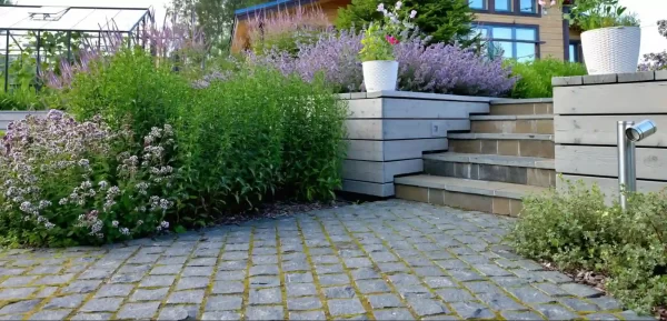 Natural cobblestone pavers create an organic and textured path that contrasts beautifully with delicate purple flowers.