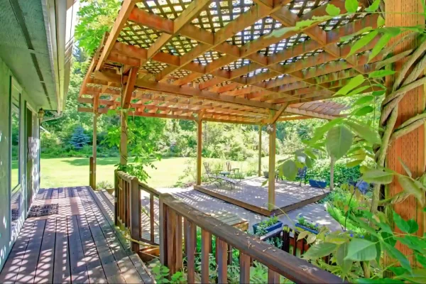 A lattice pergola draped with climbing plants creates a romantic ambiance for this multi-level backyard deck.