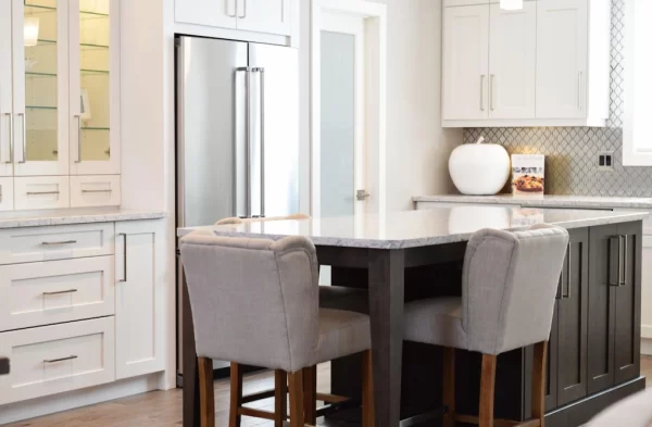 In this Shaker-style kitchen, dark-toned island cabinets contrast with white wall cabinets to create a dining area that feels separate.