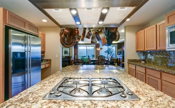 A kitchen island with a granite countertop and built-in gas stove combines practicality and visual appeal.