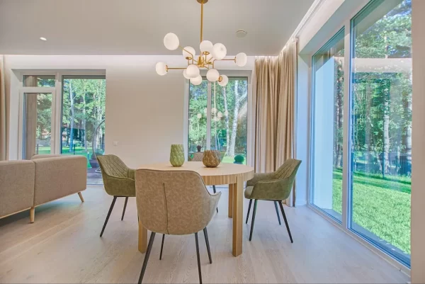 This mid-century modern dining area feels like part of the great outdoors with its neutral color scheme and surrounding view.