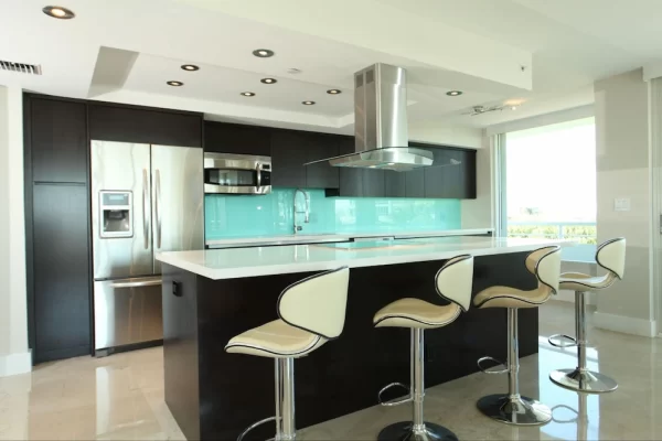 Dark cabinetry, stainless steel, and an aqua backsplash give this kitchen a vibrant, contemporary style.