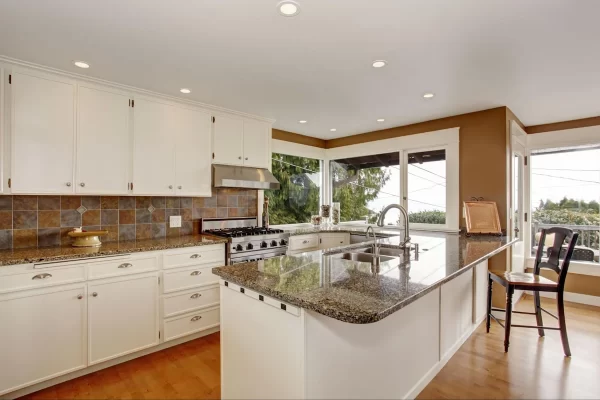 Plain white cabinets with subtle metallic hardware add brightness to this warm kitchen. 