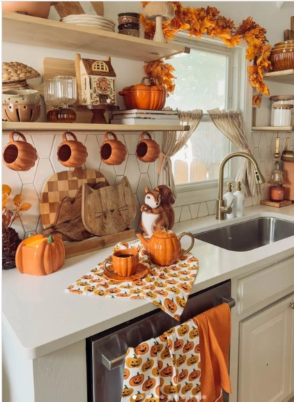 This kitchen is overflowing with fall spirit! Pumpkin-shaped tableware, linens, and vibrant orange hues create a festive and fun atmosphere.