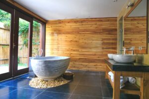 horizontal wood board paneling behind vessel bathtub and sinks