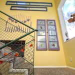 Stair landing decor that includes window frames with photos, mirrors, and more